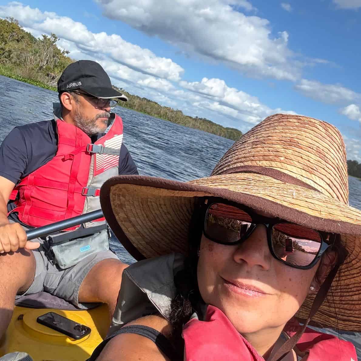 Couple wearing life jackets paddling a tandem kayak on the water at De Leon Springs State Park.