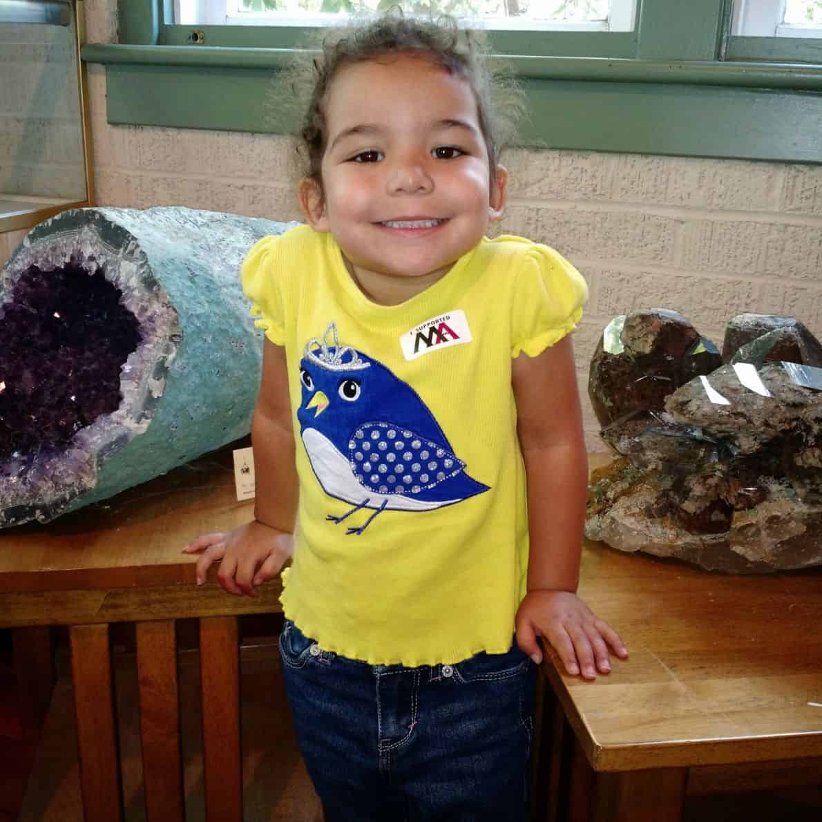 Young child smiling between large crystal geodes inside a museum display